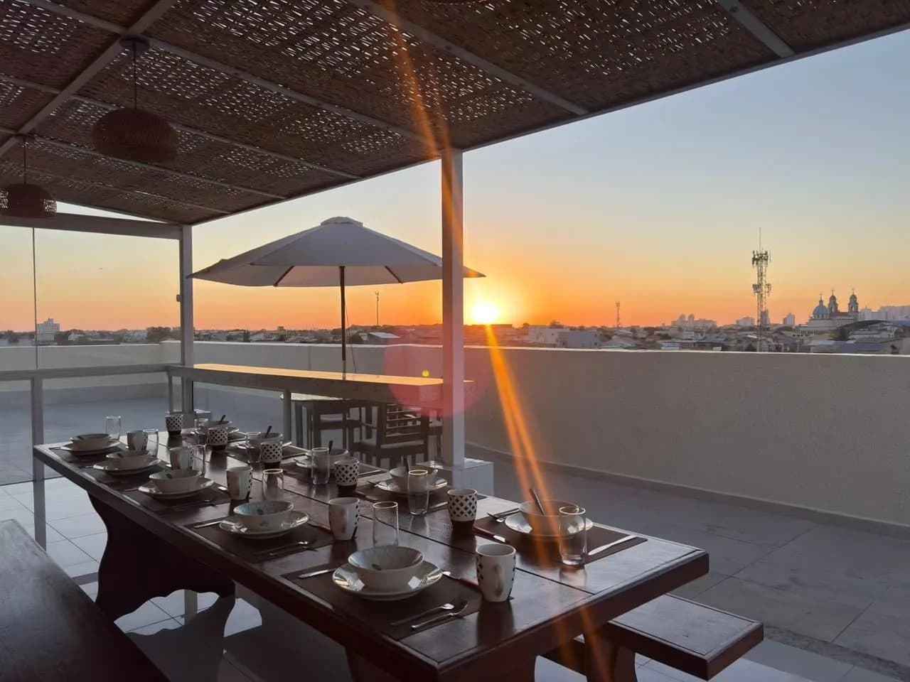 Pôr do sol visto do rooftop da Terra Hospedagem, com mesa posta para o café da manhã